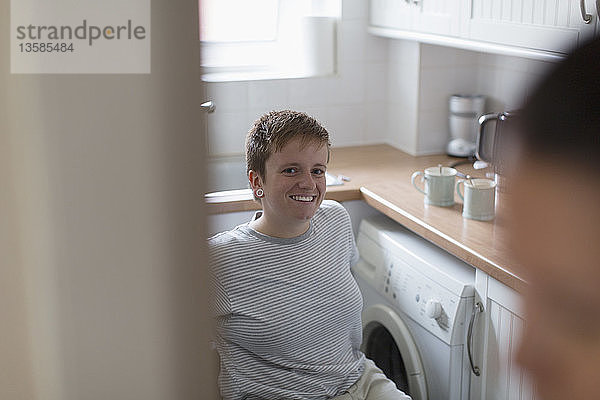 Porträt einer selbstbewussten jungen Frau im Rollstuhl in einer Wohnküche