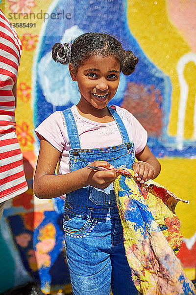 Porträt lächelnd Mädchen malen lebendige Wandmalerei auf sonnigen Wand