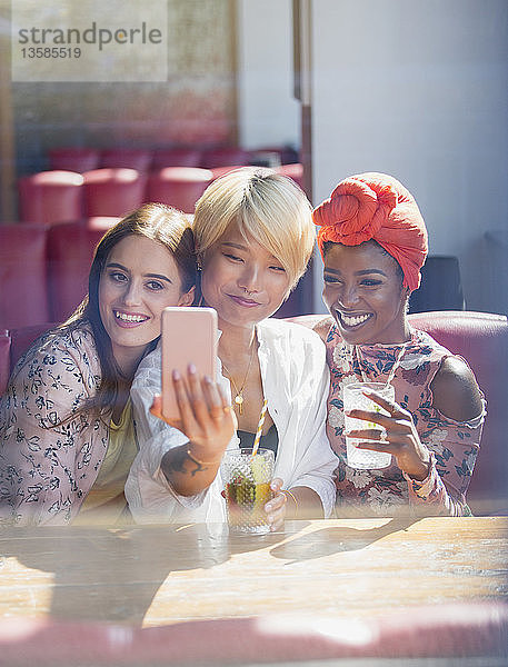 Junge Frauen Freunde trinken Cocktails und posieren für Selfie in sonnigen Restaurant