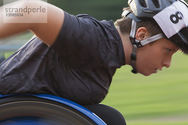 Entschlossene querschnittsgelähmte Sportlerin  die während eines Rollstuhlrennens die Sportstrecke entlang rast