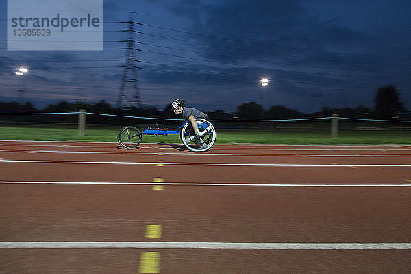 Junge querschnittsgelähmte Sportlerin  die bei einem nächtlichen Rollstuhlrennen über eine Sportstrecke rast