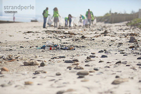 Freiwillige beseitigen Müll am sonnigen Sandstrand
