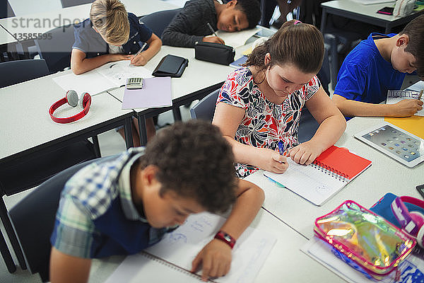 Schüler der Junior High School machen Hausaufgaben an Tischen im Klassenzimmer