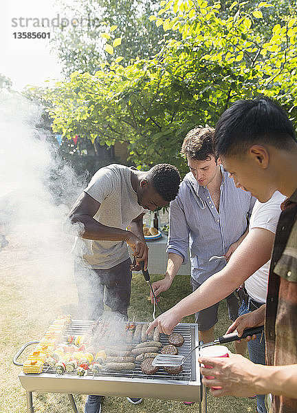 Männliche Freunde am Grill im sonnigen Hinterhof