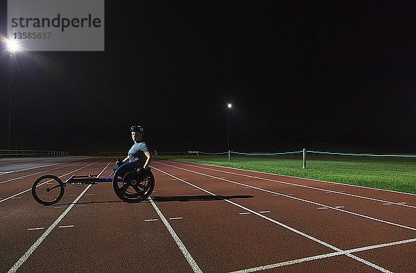 Porträt einer selbstbewussten jungen querschnittsgelähmten Athletin  die auf einer Sportbahn für ein Rollstuhlrennen trainiert