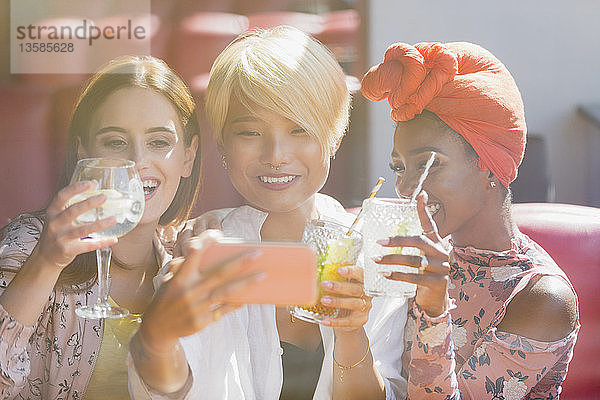 Junge Frauen Freunde trinken Cocktails und nehmen Selfie mit Smartphone in sonnigen Bar