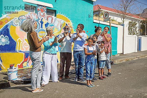 Fröhliche Freiwillige aus der Gemeinde feiern das gemalte Wandbild an der sonnigen Stadtmauer