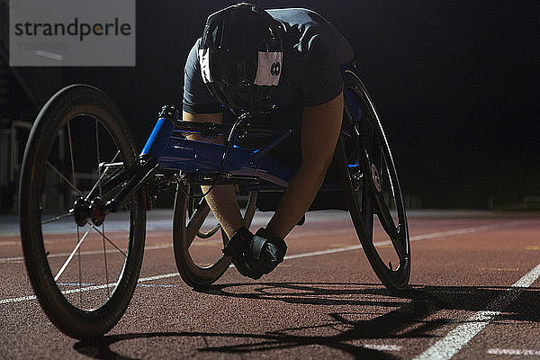 Müde querschnittsgelähmte Athletin ruht sich nach einem nächtlichen Rollstuhlrennen auf der Sportbahn aus