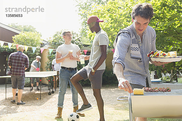 Männliche Freunde beim sommerlichen Grillen im Hinterhof