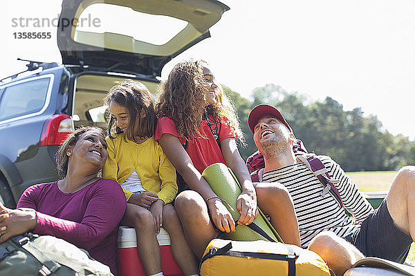Glückliche Familie mit Campingausrüstung auf dem Rücksitz des Autos