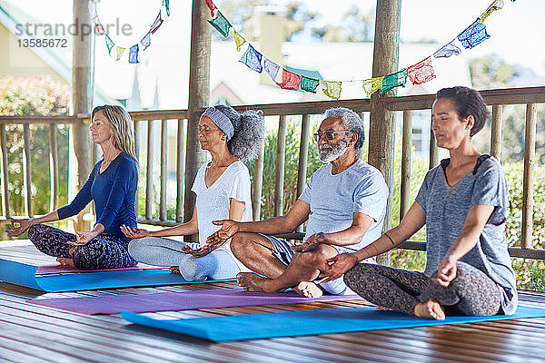 Gelassene Menschen meditieren in einer Hütte während eines Yoga-Retreats