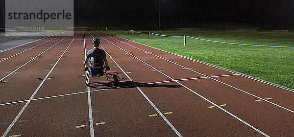 Querschnittsgelähmter trainiert nachts auf einer Sportbahn für ein Rollstuhlrennen