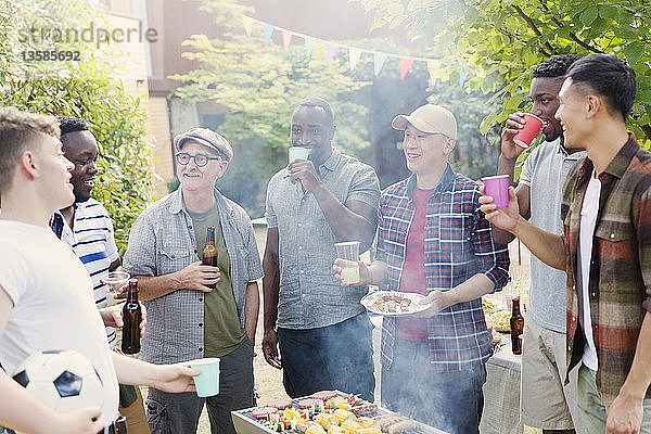 Männliche Freunde trinken Bier am Grill im Hinterhof