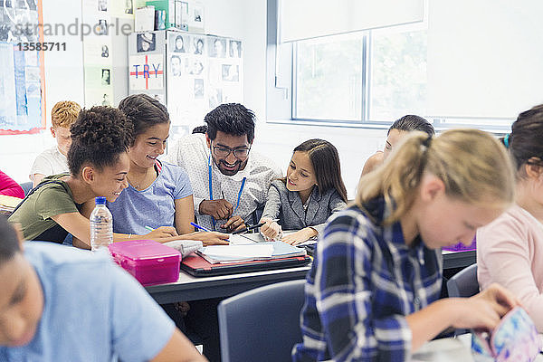 Lehrerin hilft Schülern der Junior High School am Schreibtisch im Klassenzimmer