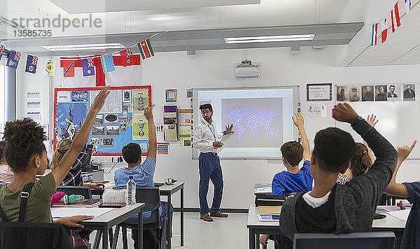 Schüler der Junior High School heben die Hände für den Lehrer  der den Unterricht im Klassenzimmer leitet