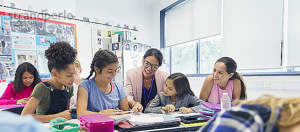 Weibliche Lehrerin und Junior High School Mädchen Schüler am Schreibtisch im Klassenzimmer