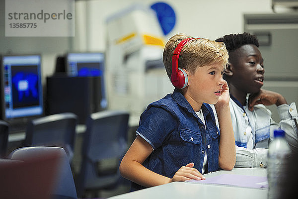 Konzentrierter Junge der Junior High School mit Kopfhörern im Klassenzimmer