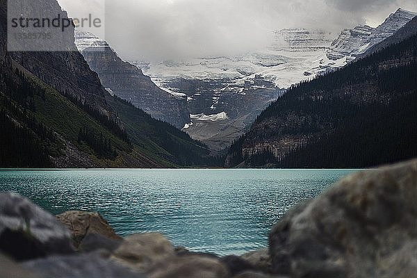 Panoramablick auf majestätische Berge jenseits eines ruhigen blauen Sees  Lake Louise  Alberta  Kanada