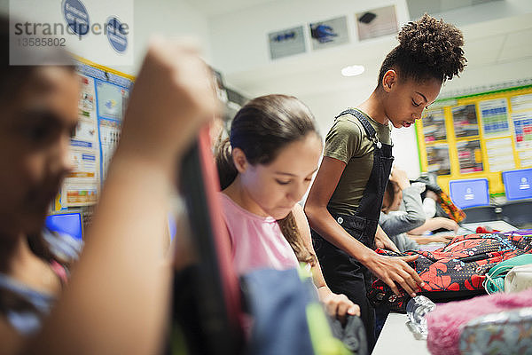 Schülerin der Junior High School mit Rucksäcken im Klassenzimmer