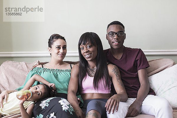 Porträt glückliches lesbisches Paar und Kinder auf Wohnzimmersofa