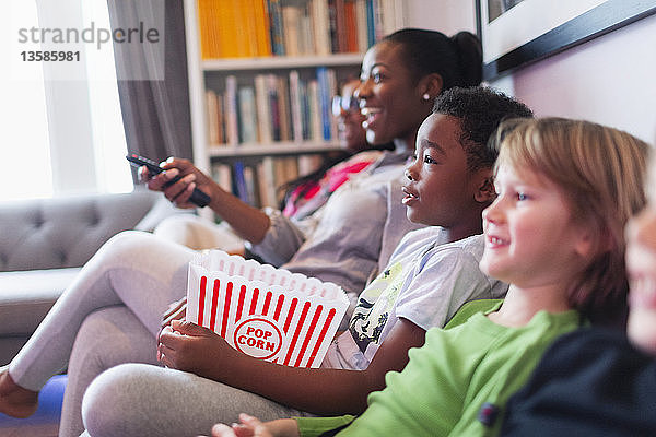 Familie und Freunde schauen einen Film und essen Popcorn auf dem Sofa im Wohnzimmer