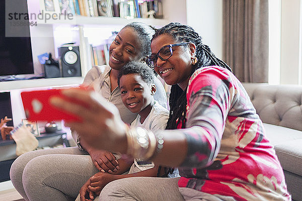 Mehrgenerationenfamilie macht Selfie mit Fotohandy im Wohnzimmer
