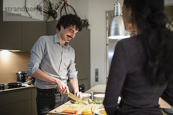 Ehepaar schneidet Gemüse und kocht Abendessen in der Wohnküche