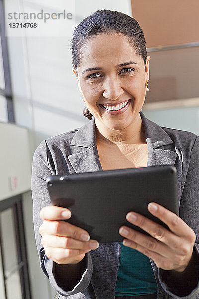 Porträt einer Geschäftsfrau  die mit einem Tablet lächelt