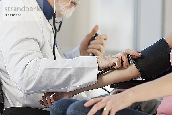 Arzt kontrolliert den Blutdruck eines Patienten
