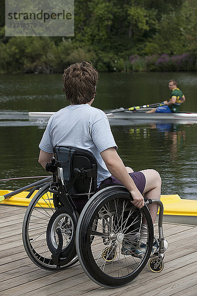 Frau mit Querschnittslähmung sitzt im Rollstuhl auf dem Steg