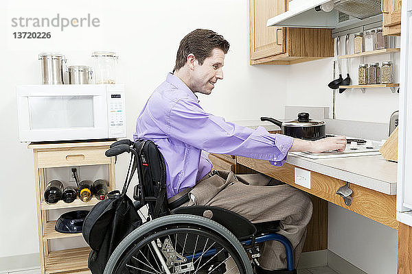 Ein Mann im Rollstuhl mit einer Rückenmarksverletzung stellt die Hitze an einem zugänglichen Ofen ein