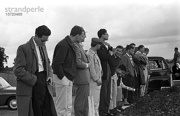 Eine Gruppe von Fahrern bei den Testfahrten für den Großen Preis von Großbritannien. 2. von links Dan Gurney  in leichter Kleidung mit Mütze Masten Gregory  dann Nick Syrett BRSCC Offizieller Mitte  Bruce McLaren am nächsten zur Kamera  Silverstone  England 16. Juli 1960.