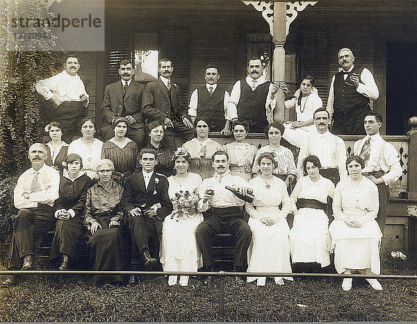 Merrick  Massachusetts: ca. 1890 Ein Porträt eines frisch verheirateten Paares  das mit einer Flasche und seinen Familien und Freunden feiert.