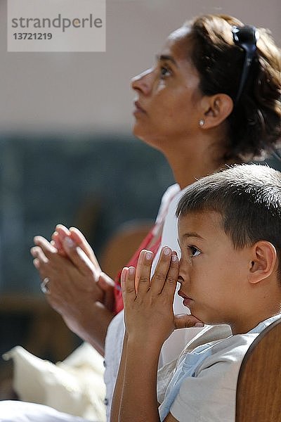 Mutter und Sohn beten in einer Kirche.