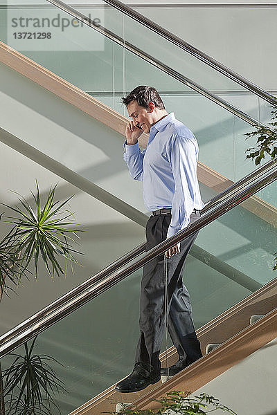 Geschäftsmann  der mit seinem Handy telefoniert und eine Treppe hinuntergeht