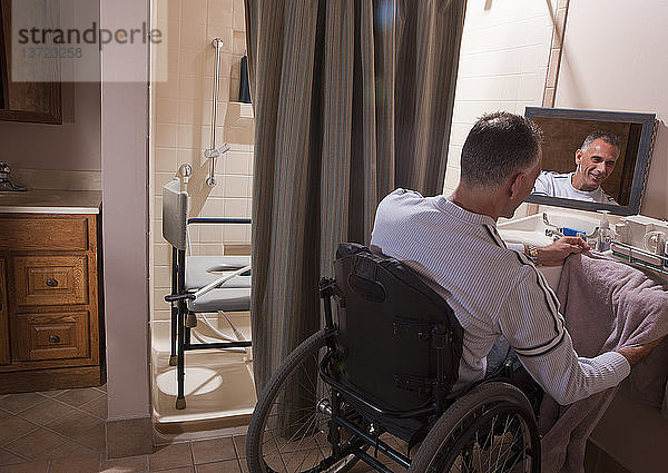 Mann mit Rückenmarksverletzung im Rollstuhl  der ein Handtuch benutzt