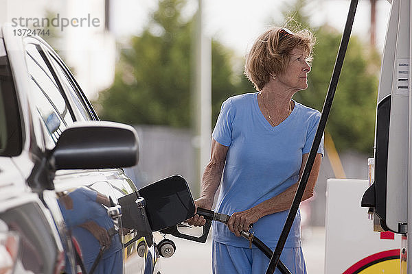 Frau tankt Auto an einer Tankstelle