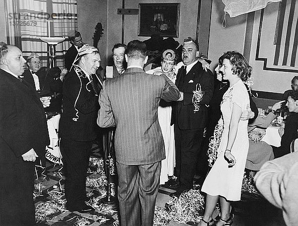 Vereinigte Staaten: 1. Januar 1948 Eine Gruppe von Menschen auf einer Silvesterparty im Hotel Stone singt und hat viel Spaß.