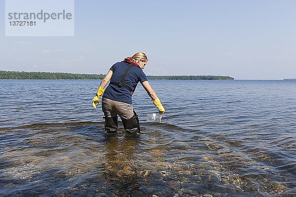 Ingenieur für öffentliche Arbeiten entnimmt Wasserproben aus einem Stausee