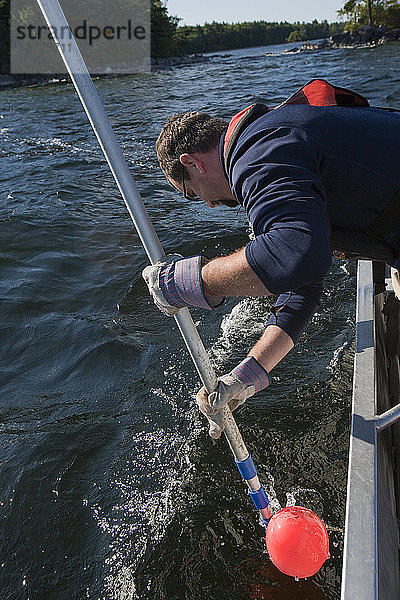 Wissenschaftler zieht mit einem Gaff eine an einer Algenprobe befestigte Boje hoch