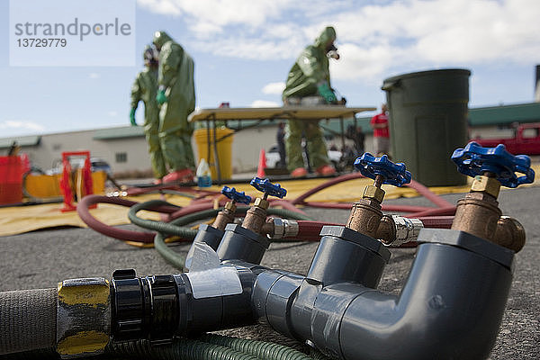 Wasserverteiler im HazMat-Dekontaminationsbereich mit HazMat-Feuerwehrleuten im Hintergrund