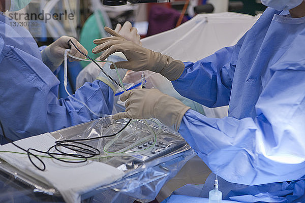 Chirurgische Technikerin reicht dem Arzt ein Phako-Handstück während einer Kataraktoperation