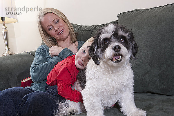 Frau gebärdet das Wort ´love´ in amerikanischer Zeichensprache  während ihr Sohn einen Hund umarmt