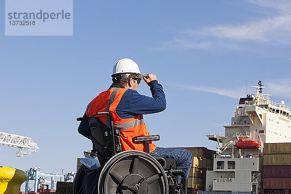 Transportingenieur im Rollstuhl bei der Inspektion von Schiffscontainern im Verschiffungshafen