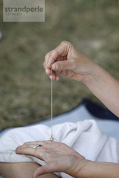 Eine Frau benutzt ein Pendel bei einem Kundalini Yoga Festival