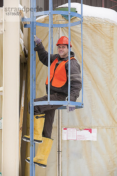 Ingenieur klettert auf einen Turm mit Sicherheitsumhausung