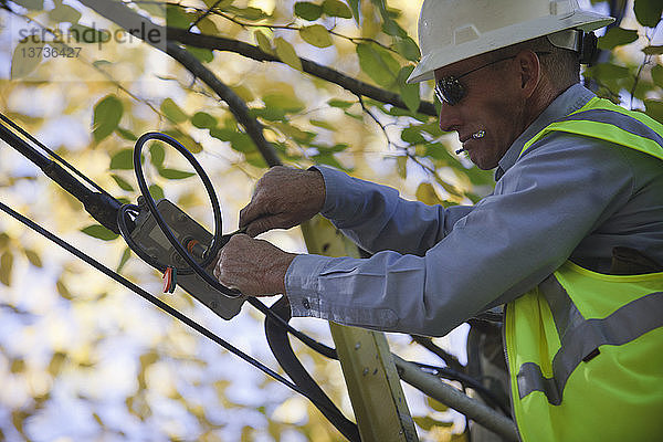 Ingenieur bei der Installation eines Kanalfilters an einem Kabelverteilerkasten an einem Strommast