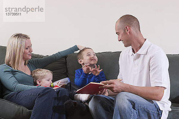 Junge gebärdet das Wort ´Family´ in amerikanischer Zeichensprache  während er mit seinen Eltern lernt