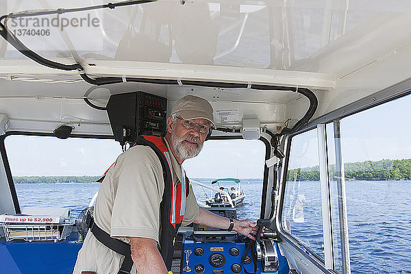 Ingenieur der öffentlichen Arbeiten steuert ein Boot zur Entnahme von Wasserproben auf einem öffentlichen Stausee