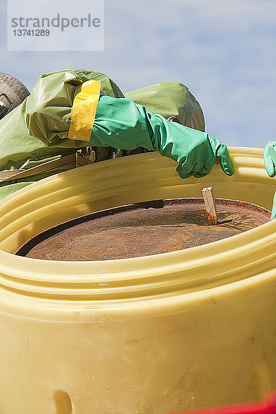 HazMat-Feuerwehrmann beim Einsetzen eines verstopften Fasses in ein Bergungsfass